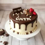 A beautifully designed chocolate smash cake with a glossy chocolate drip, decorated with strawberries, chocolate pieces, and white chocolate details.